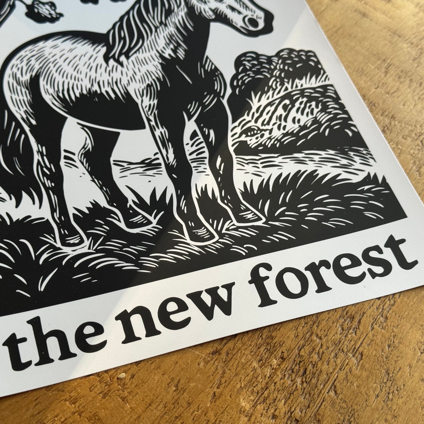 Print of a horse in a forest with 'the new forest' text on a wooden surface