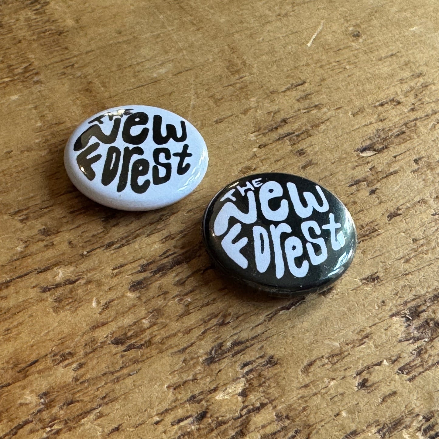 Two buttons with 'The New Forest' text on a wooden surface