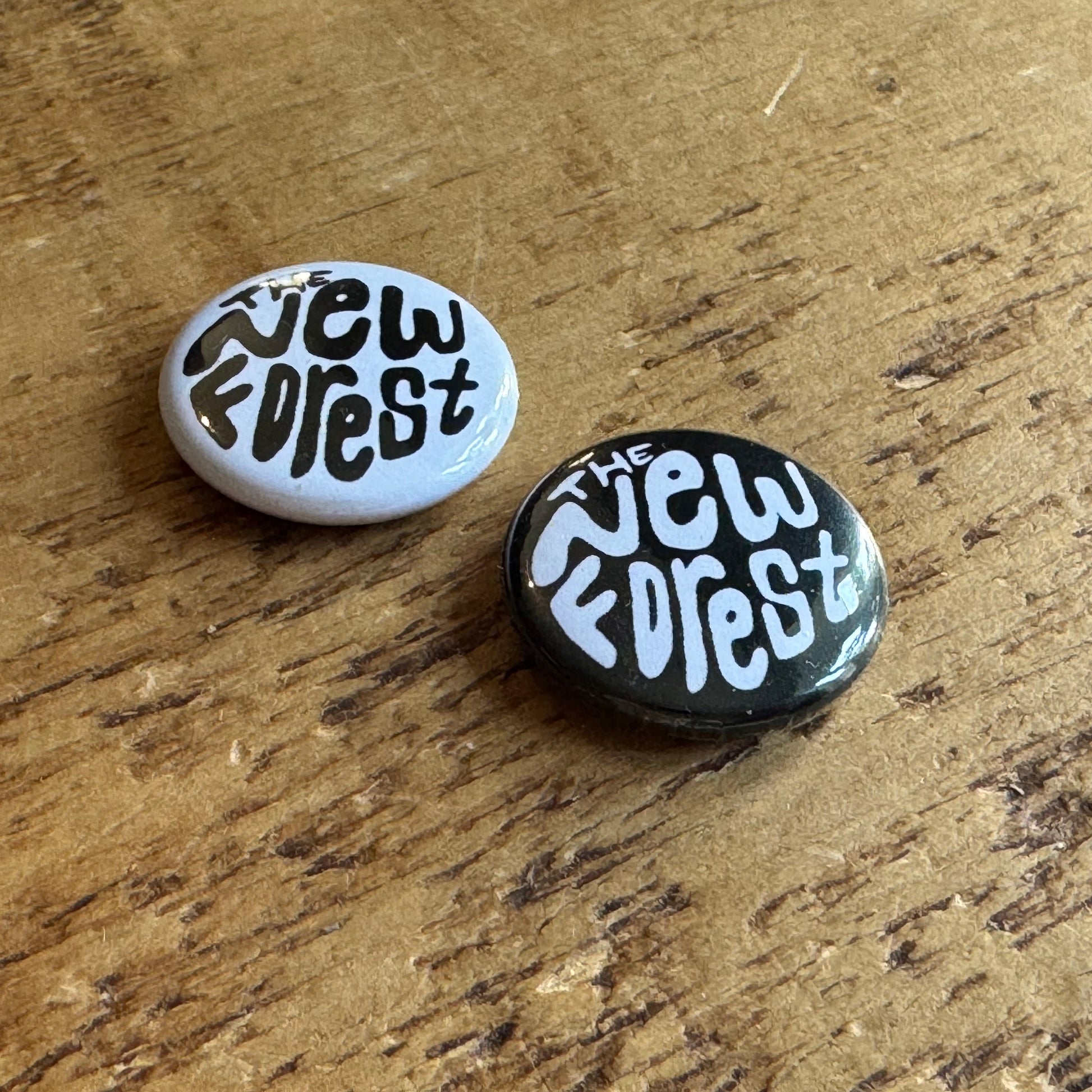 Two buttons with 'The New Forest' text on a wooden surface