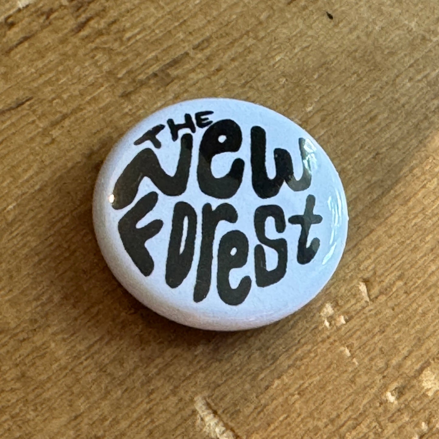 White button badge with 'The New Forest' text on a wooden surface