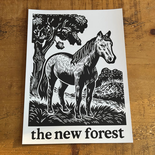 Poster with a horse illustration and 'the new forest' text on a wooden surface