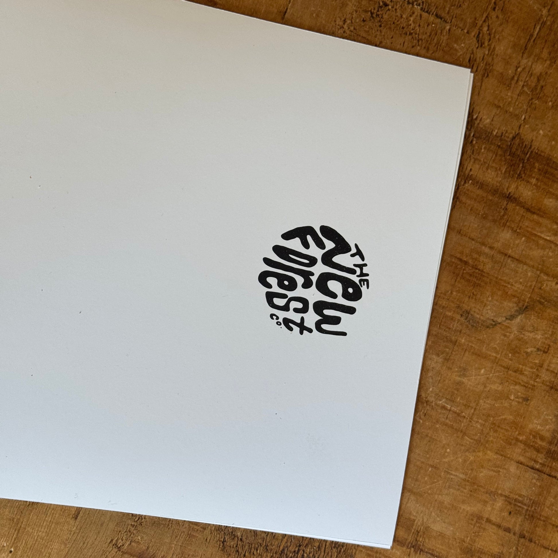 White paper with 'The New Forest' logo on a wooden surface