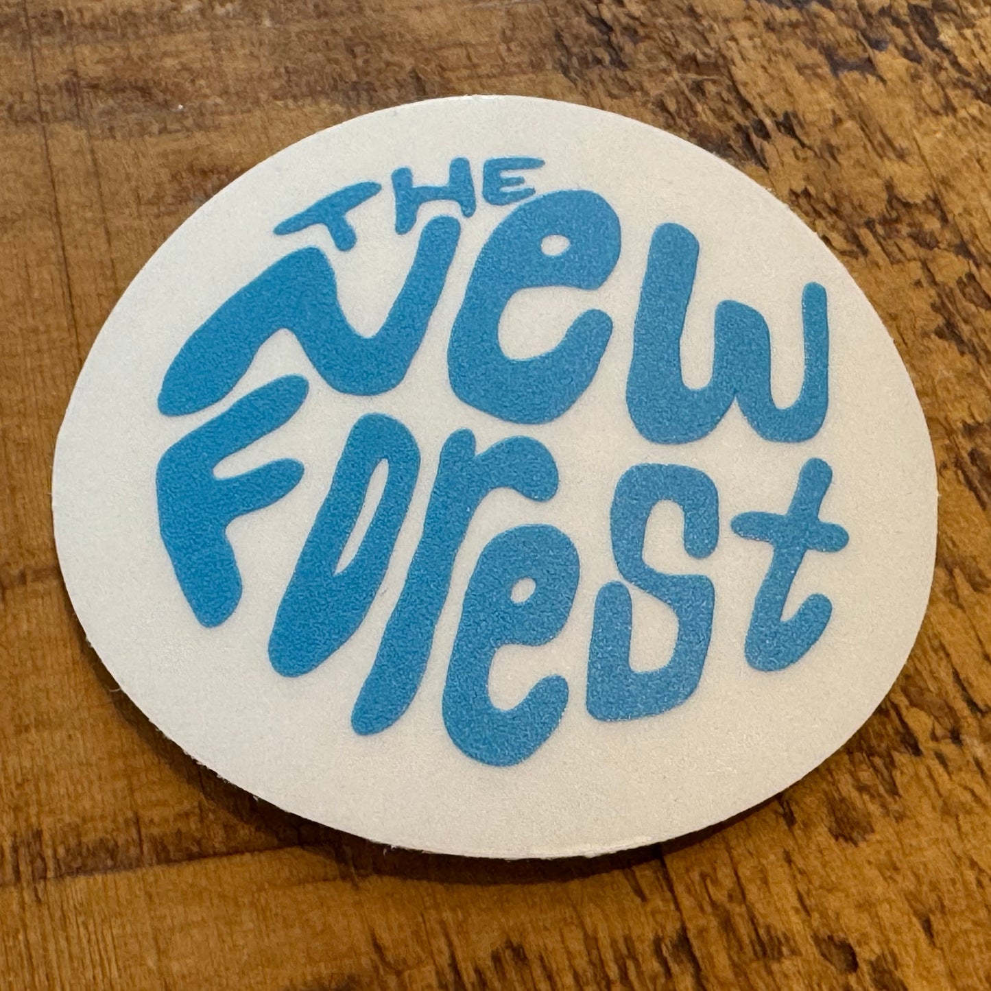 The New Forest Typography Circle Sticker (Clear) Blue on Desk
