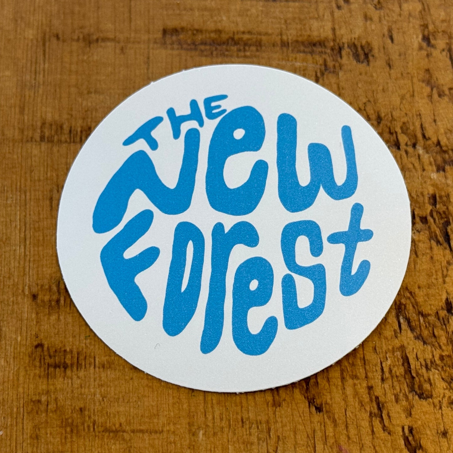 The New Forest Typography Circle Sticker (Solid) Blue/White on Desk